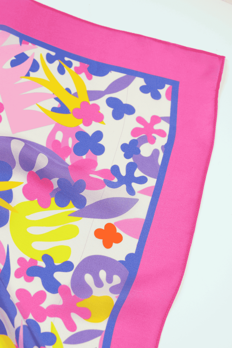 Colorful floral patterned scarf corner with pink border on a white background